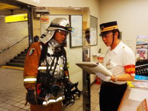 駅職員が消防士に状況報告している写真